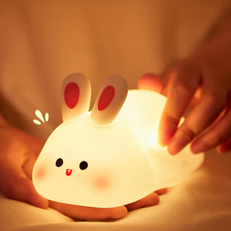 Cute rabbit-shaped night light being held by a hand with a warm glow.